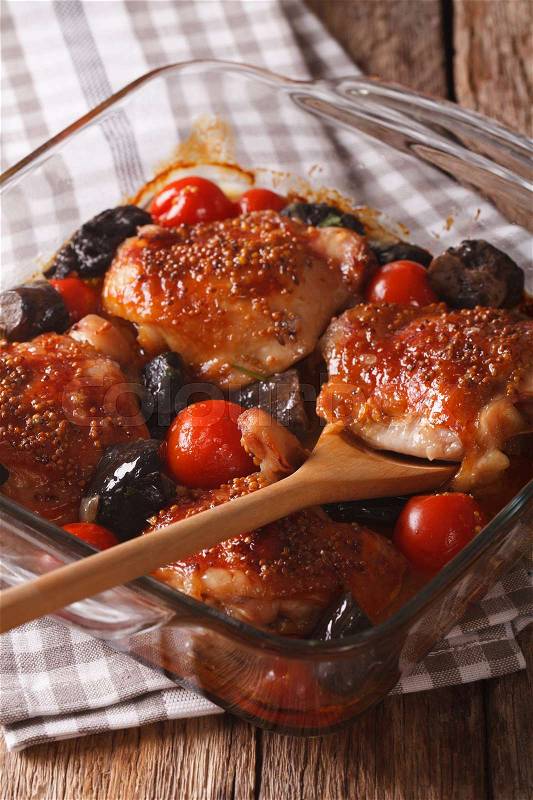 Chicken thigh baked with tomatoes and cep mushrooms close up in baking dish on the table. vertical\, stock photo
