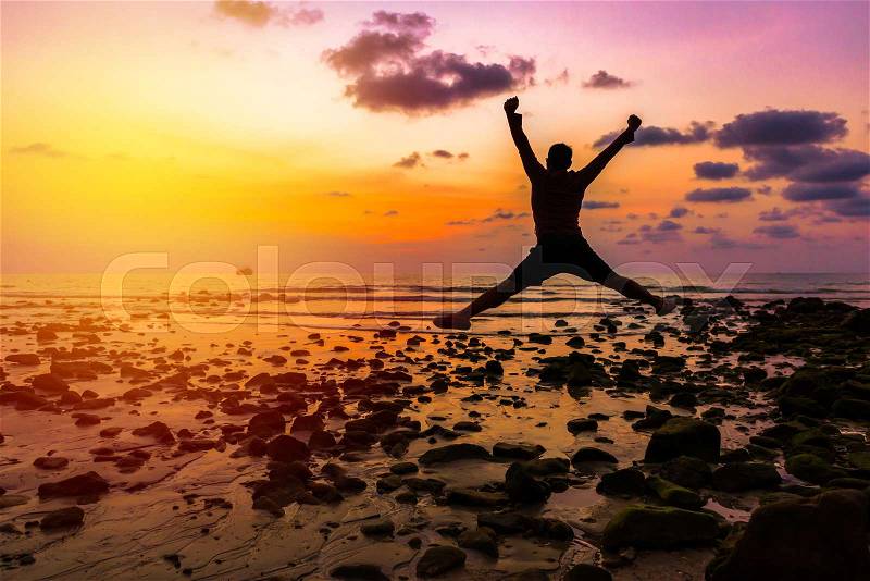 Man Happy jump with his hands up during sunset at the beach, stock photo