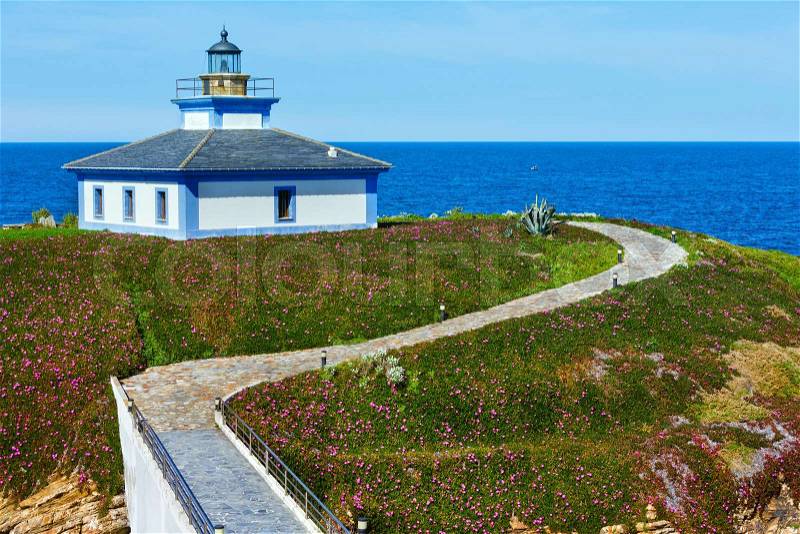 Summer ocean island Pancha coastline landscape with lighthouse and pink flowers (Spain), stock photo