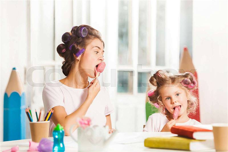 Little girl sitting with her mother and eating ice cream, stock photo