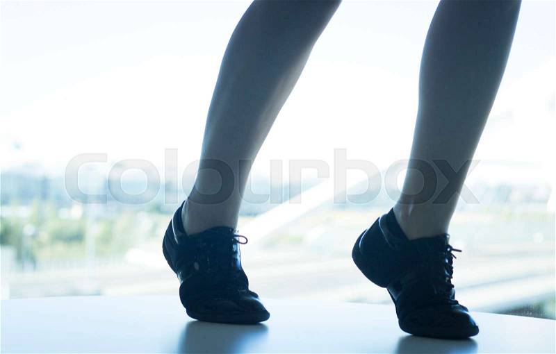 Woman dance fit teacher giving dancing class in gym in silhouette by window, stock photo