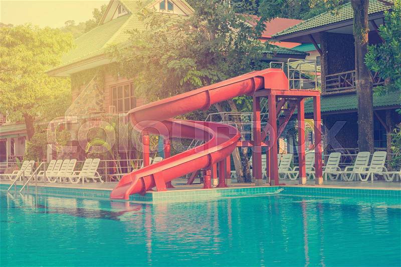 Blue swimming pool with water slide at hotel, stock photo