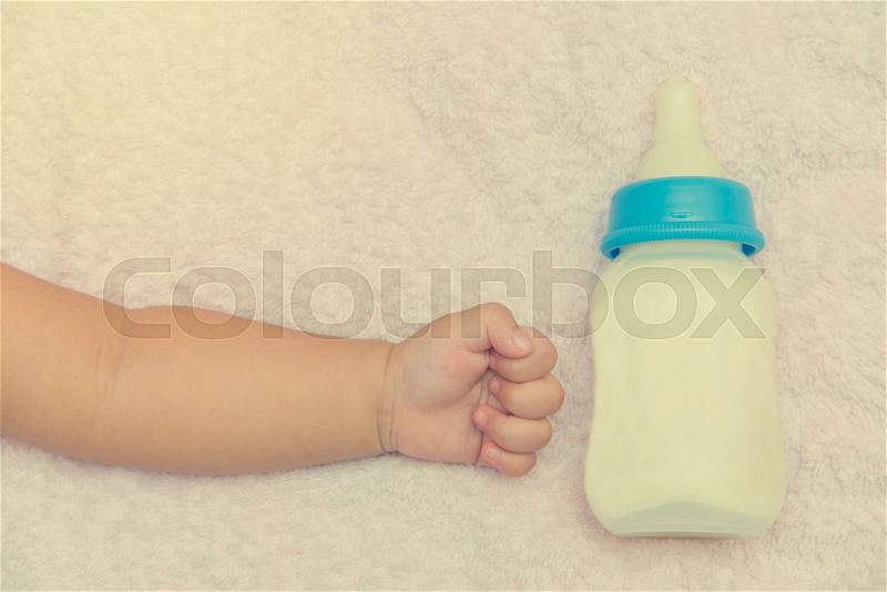 Milk bottle and hand of newborn baby girl, stock photo