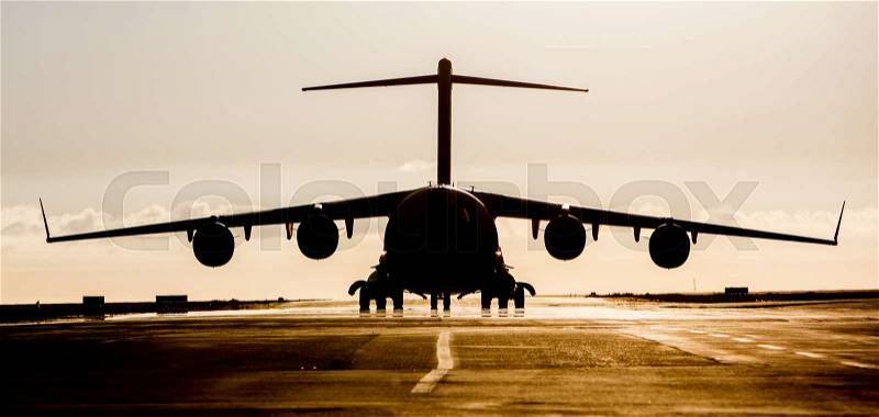 Large military cargo plane silhouette on an empty airstrip, stock photo