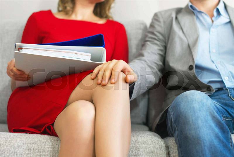 Sexual harassment at work. Man touching secretary\'s knee, stock photo