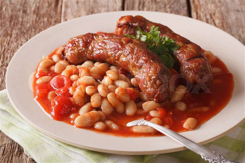 Sausages with beans in tomato sauce on a plate close-up on the table. horizontal , stock photo