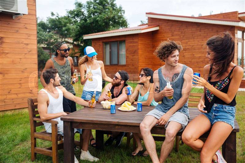 Group of happy young people drinking beer and having outdoor summer party, stock photo