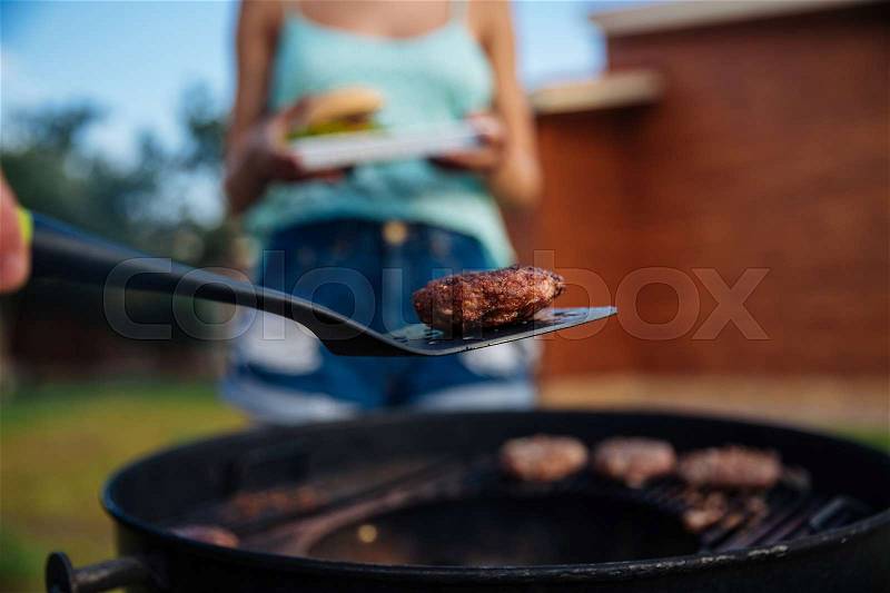 Closeup of people cooking meet on barbeque grill outdoors, stock photo