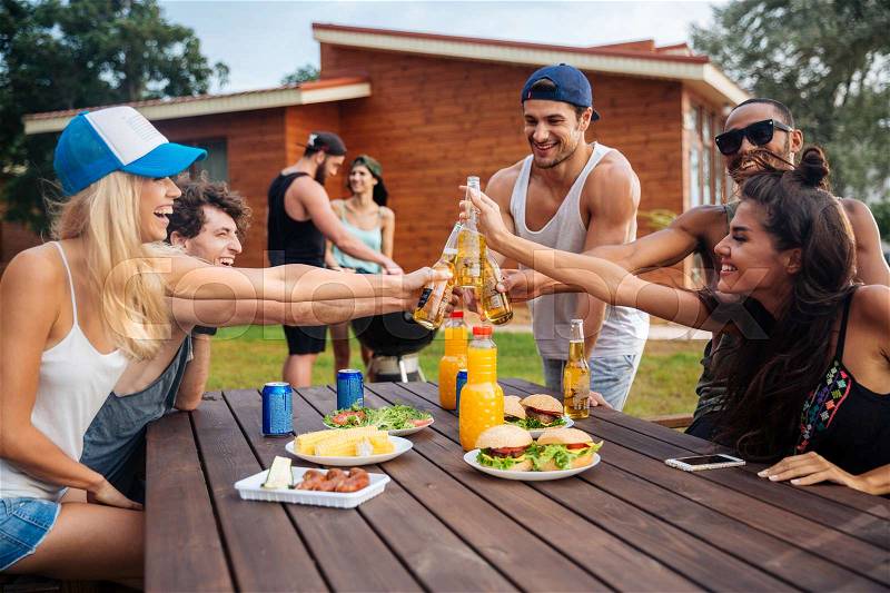 Happy group of young cheerful friends having fun at picnic outdoors, stock photo