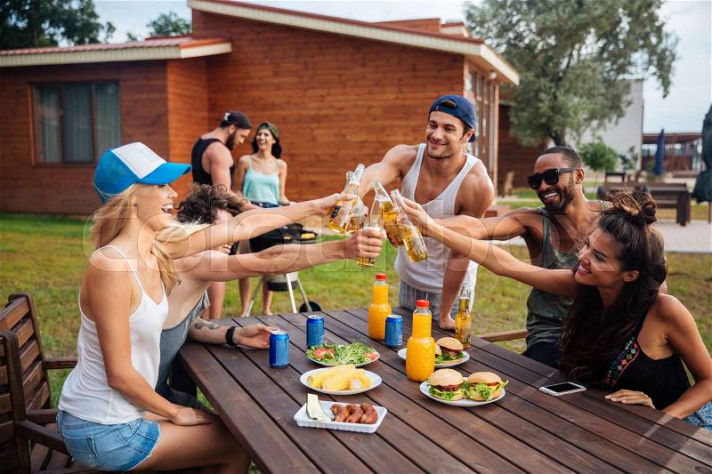 Group of cheerful young people celebrating and drinking beer on outdoor party, stock photo