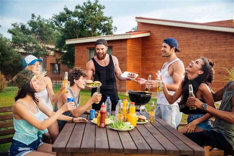 Group of happy young people laughing and having fun on barbeque party, stock photo