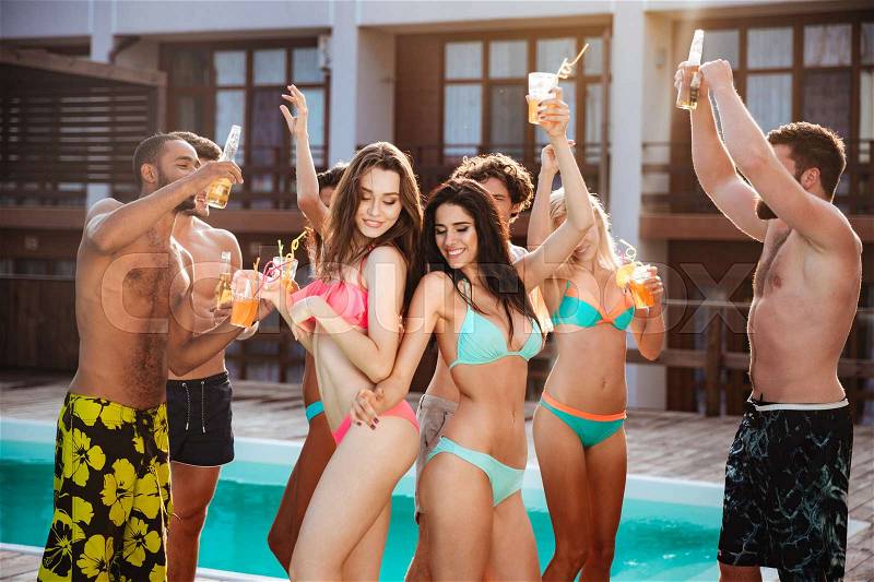 Group of best friends having fun dancing at swimming pool outdoors, stock photo