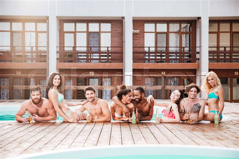 Croup of cheerful happy friends drinking beer at the pool outdoors, stock photo