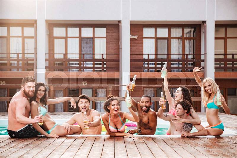 Croup of cheerful happy friends drinking beer at the pool outdoors, stock photo