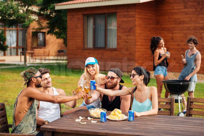 Group of happy young people celebrating and drinking outdoors, stock photo