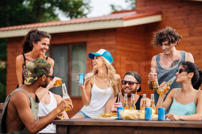 Group of cheerful young people drinking beer and soda and laughing outdoors, stock photo