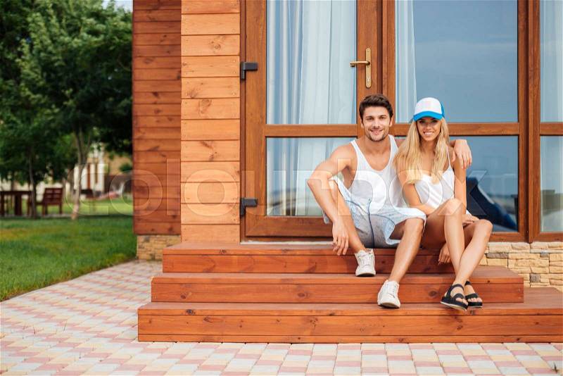 Happy young couple sitting and hugging on porch of the house, stock photo