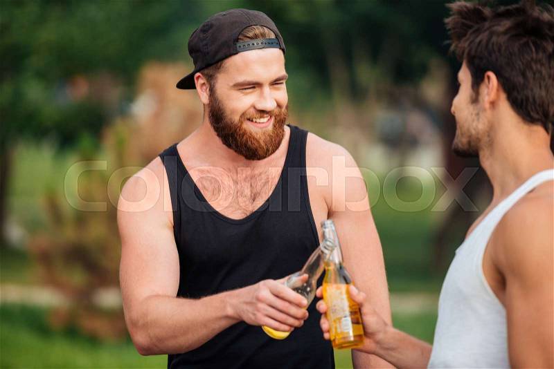 Two men holding a beer bottles outdoors, stock photo