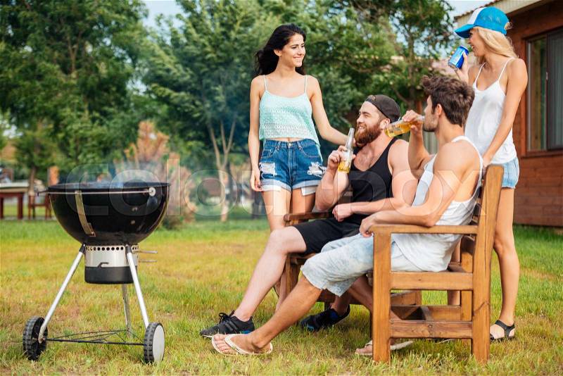 Group of young teenagers chatting while preparing barbecue grill in park zone, stock photo