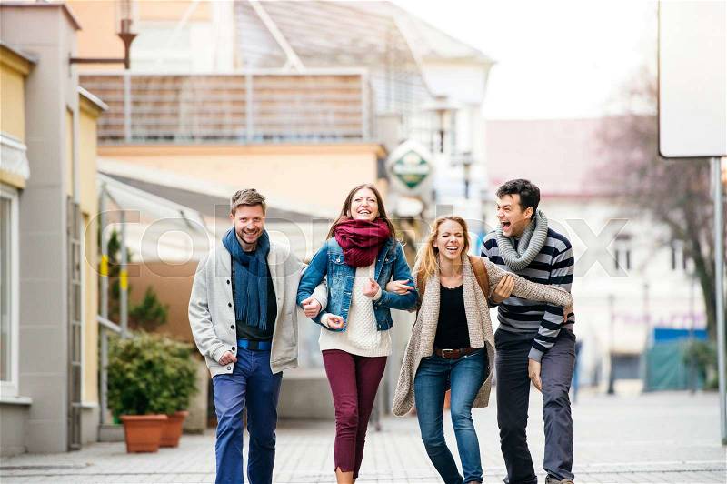 Group of young people laughing, having fun outside in town, stock photo
