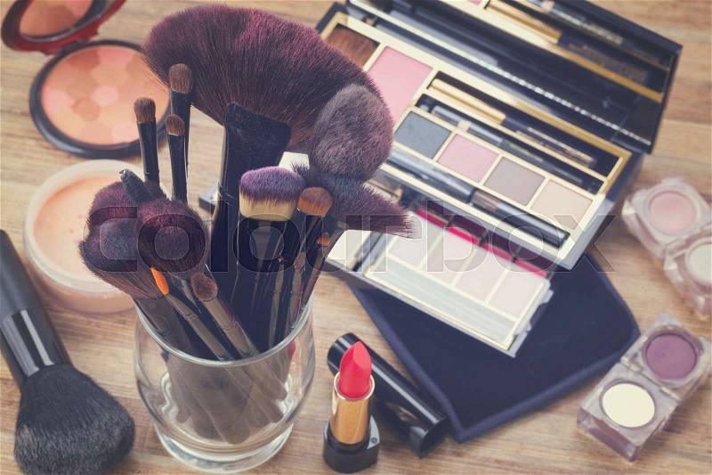 Glass can with brushes and make up products on wooden table, retro toned, stock photo