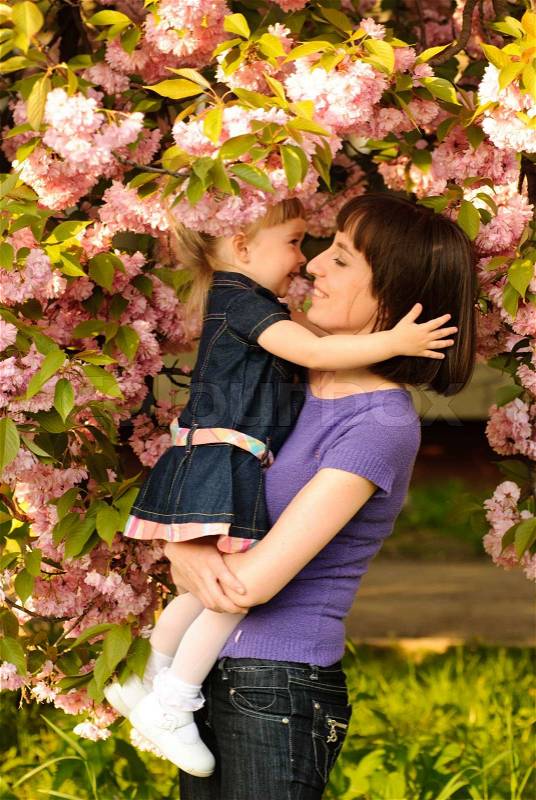 Mother and daughter in garden, under the sakura tree. Spring, stock photo