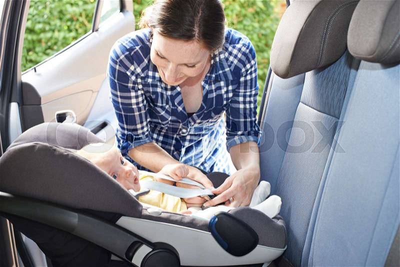Mother Putting Baby Into Car Seat For Journey, stock photo
