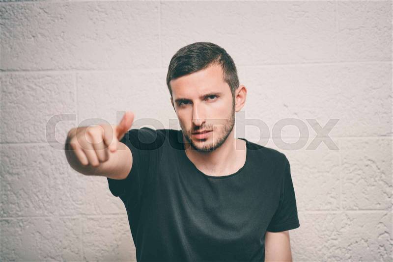 Young man showing his index finger towards the camera, stock photo
