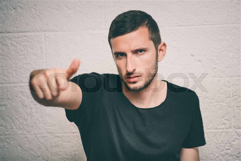 Young man showing his index finger towards the camera, stock photo