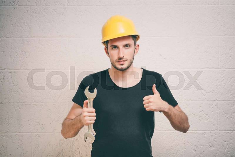 Portrait of young handyman holding a wrench, stock photo