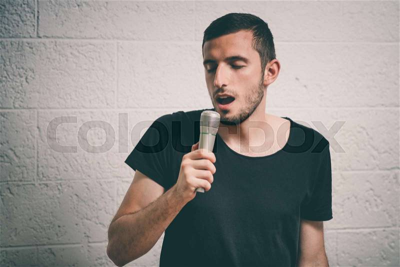 Boy Rocking Out. Image of a handsome man singing to the microphone. Emotional portrait of an attractive guy, stock photo