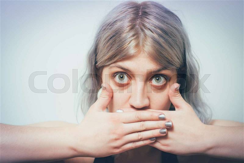 Successful stylish girl covers her mouth with her hands, isolated in the studio, stock photo