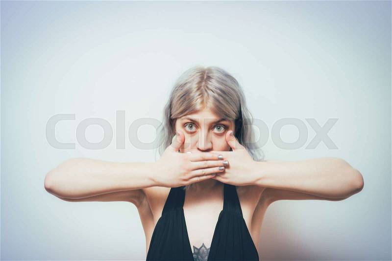 Successful stylish girl covers her mouth with her hands, isolated in the studio, stock photo