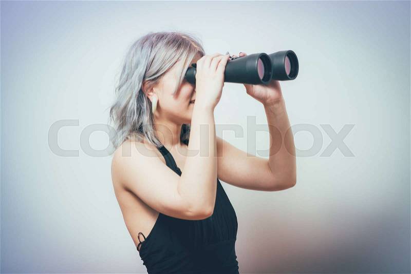 Portrait of young girl looking through a binoculars, stock photo