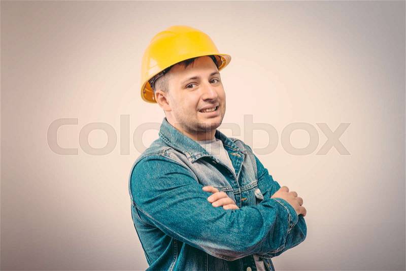 Handsome young man with protective helmet on his head and arms crossed, stock photo