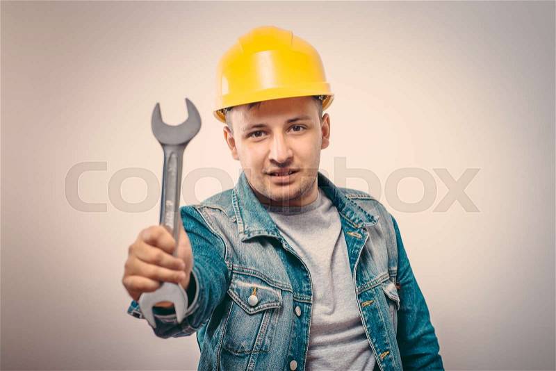 Portrait of young handyman holding a wrench, stock photo