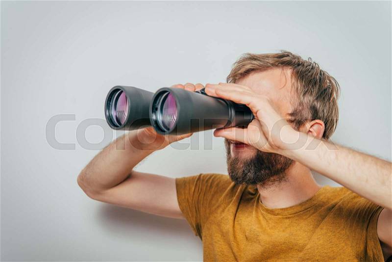 Man with binoculars. gray background, stock photo