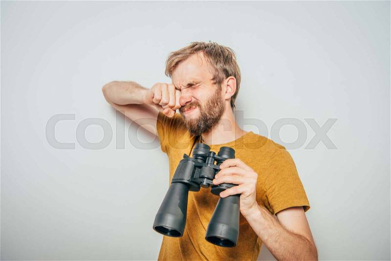 Man with binoculars. gray background, stock photo