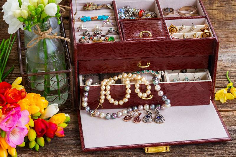 View of Jewellery in treasure box on wooden table with blooming fresia flowers, stock photo