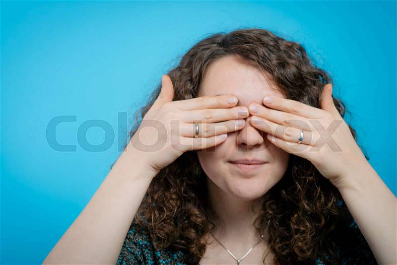 Woman closes eyes with her hands, stock photo