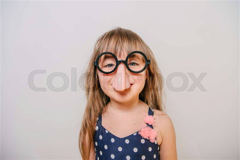 A little girl with glasses. funny glasses humor. little girl laughing. girl clown. Girl looks funny, stock photo