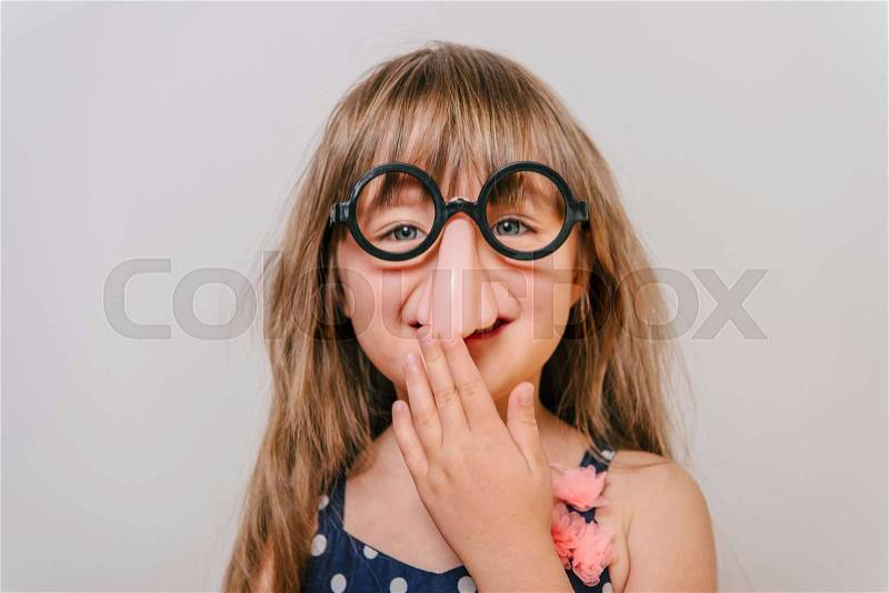 A little girl with glasses. funny glasses humor. little girl laughing. girl clown. Girl looks funny, stock photo