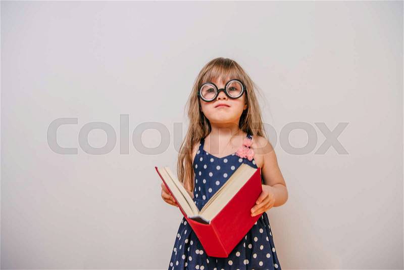 Girl with books. little girl in polka-dot dress. girl with thick book. a little girl with glasses and a book. girl reading. Girl learns. Little Girl tired to learn, stock photo