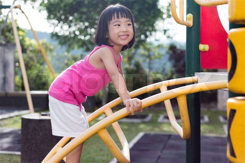 Asian Chinese little girl climbing at outdoor playground, stock photo
