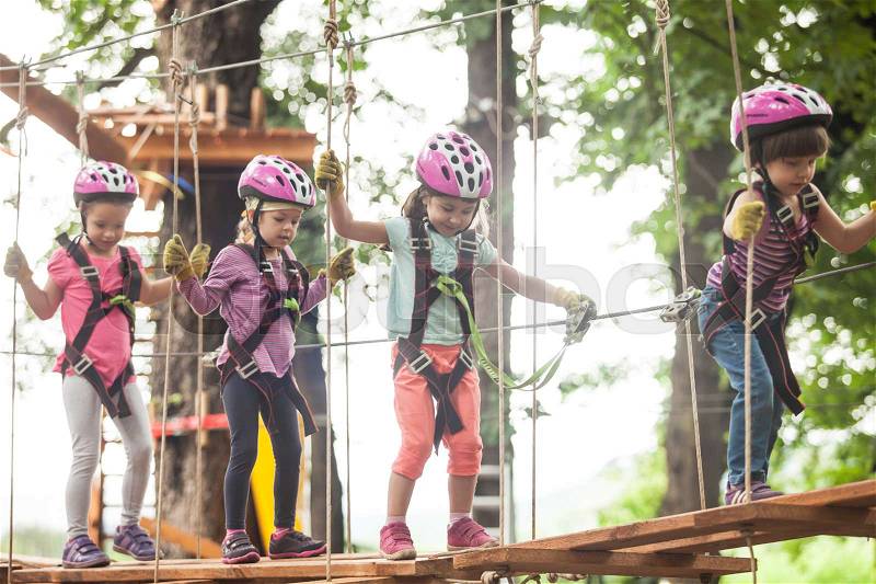Kids on obstacle course in adventure park in mountain helmet and safety equipment, stock photo