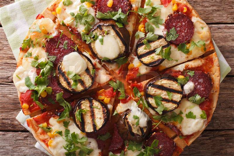 Pizza with eggplant, salami, corn and mozzarella close up on a wooden board. horizontal view from above , stock photo