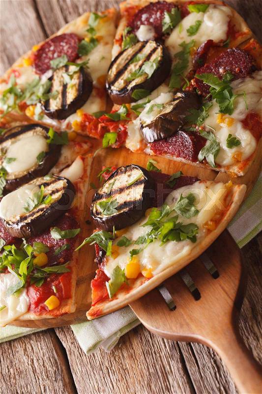 Italian pizza with eggplant, sausage, corn and mozzarella close up on a wooden board. vertical\, stock photo
