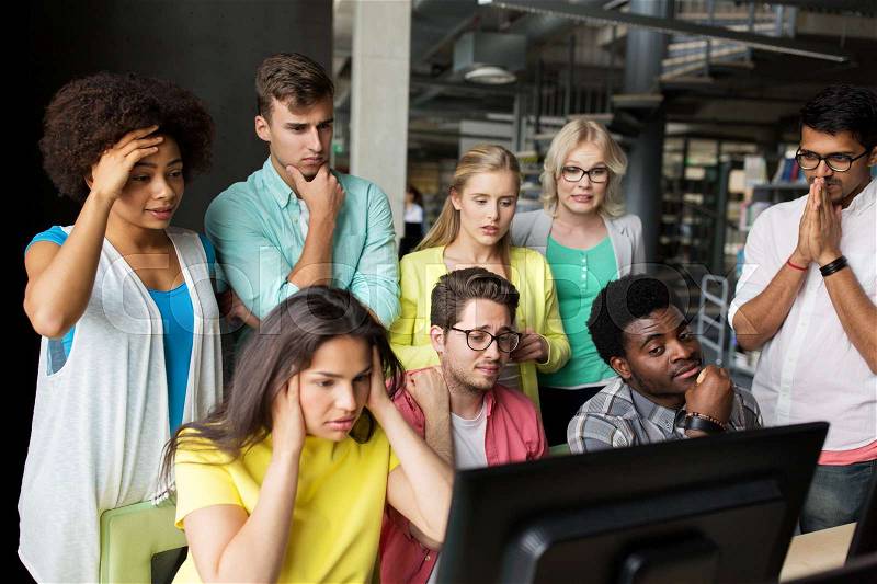 People, education, technology, fail and school concept - group of international students with computers at library in university having some problem, stock photo