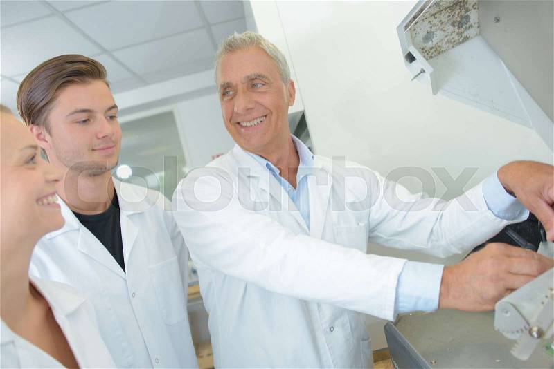 Senior technician joking with male and female students, stock photo