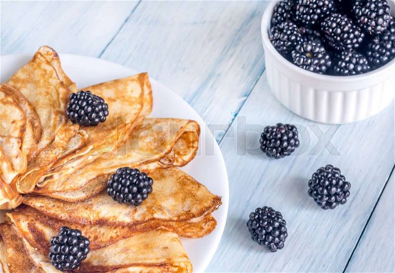 Crepes with blackberries on the wooden table, stock photo
